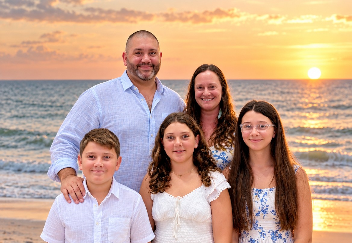 A family of five together on the beach at sunset